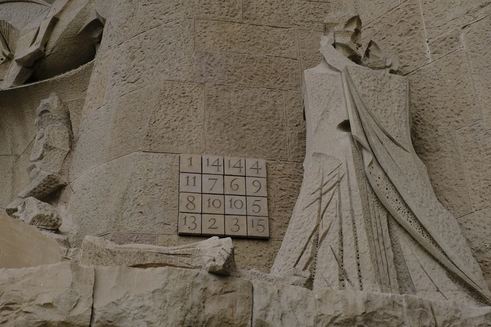 The Kiss of Judas sculpture next to the magic square on the Passion facade of the Sagrada Família in Barcelona.