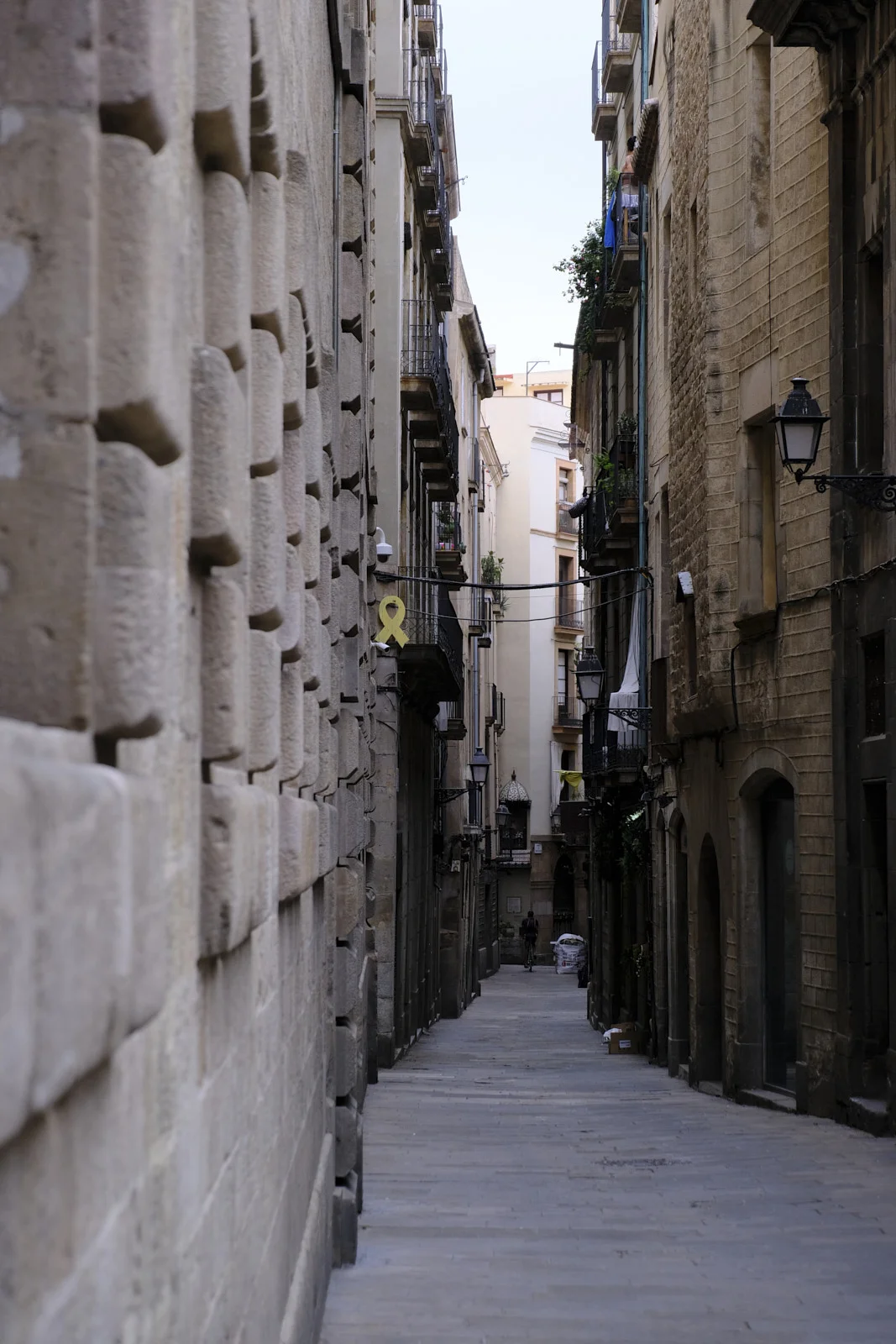 A narrow lane in El Born, Barcelona, with a high stone wall along one side.