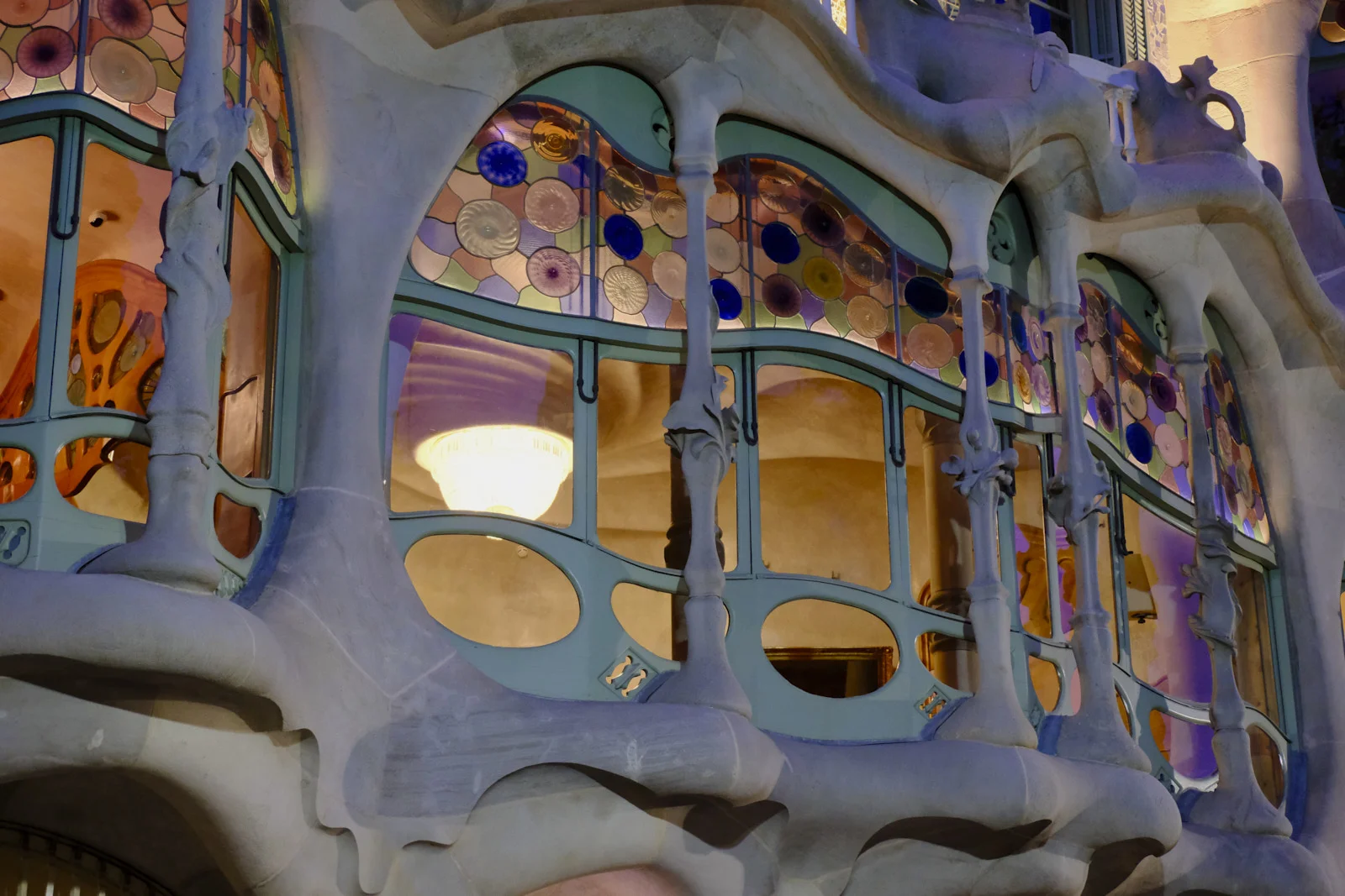 Curved windows and stone columns on the facade of Casa Batlló in Barcelona.