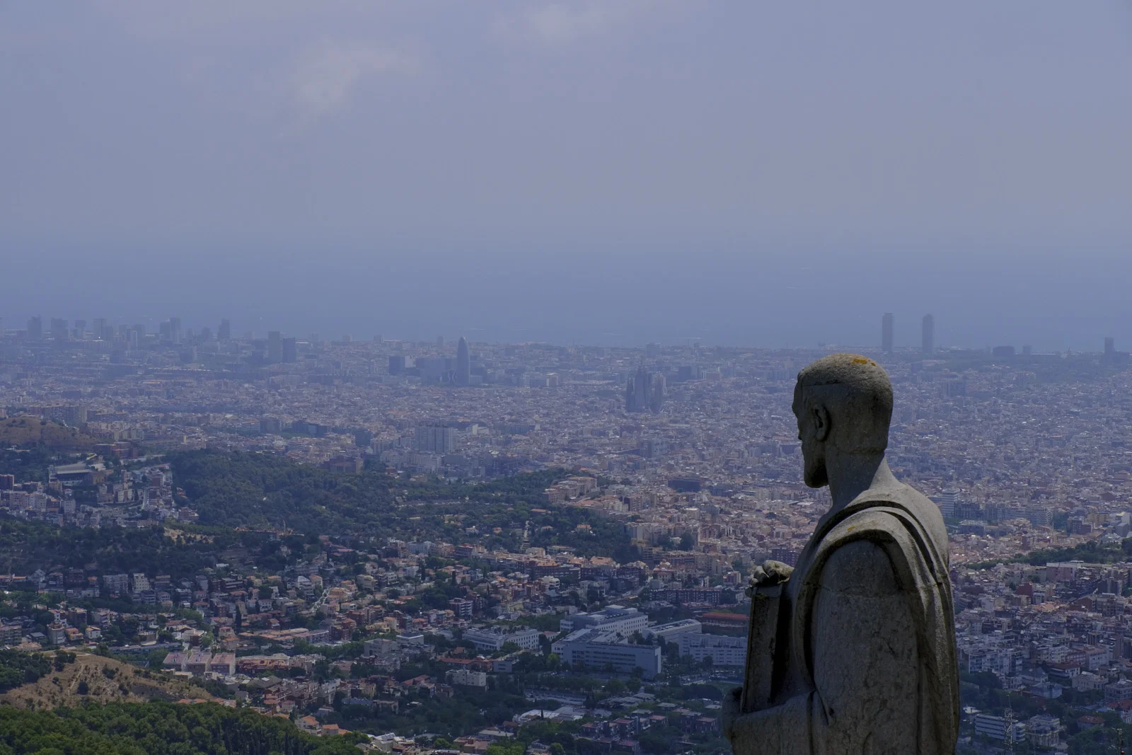 A stone apostle at the Sagrat Cor on Tibidabo, with Barcelona and the Sagrada Família beyond.