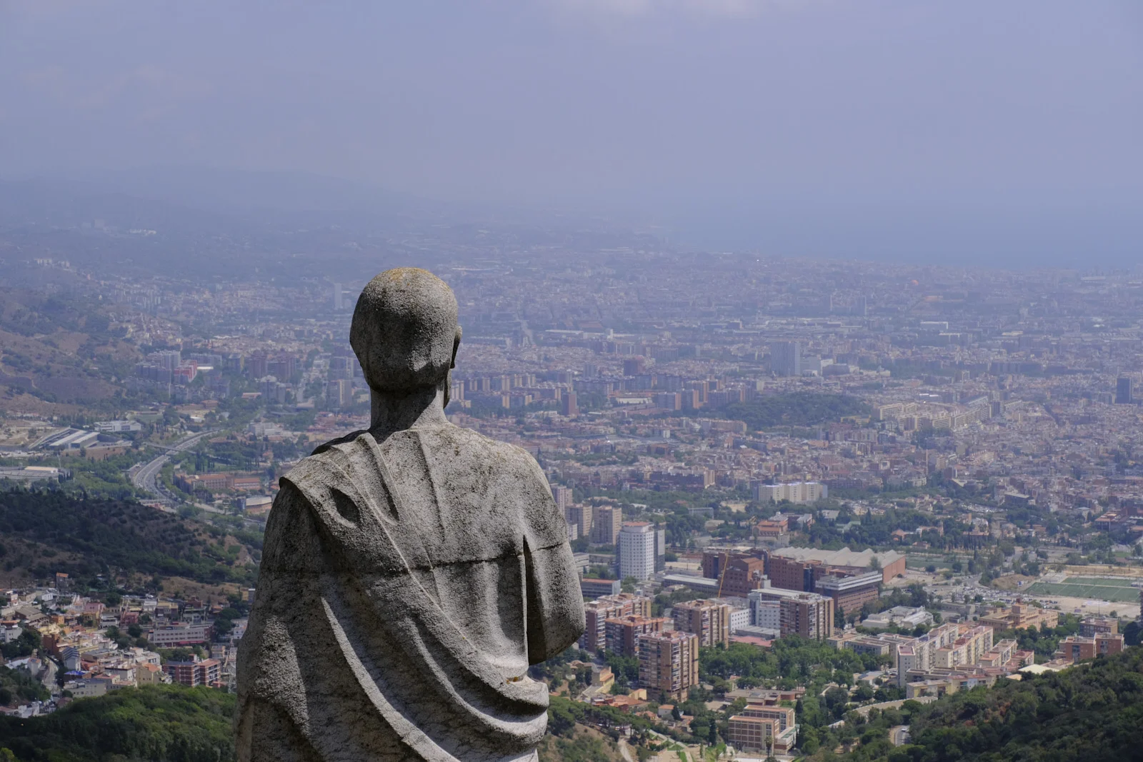 A stone apostle seen from behind on Tibidabo, facing Barcelona.