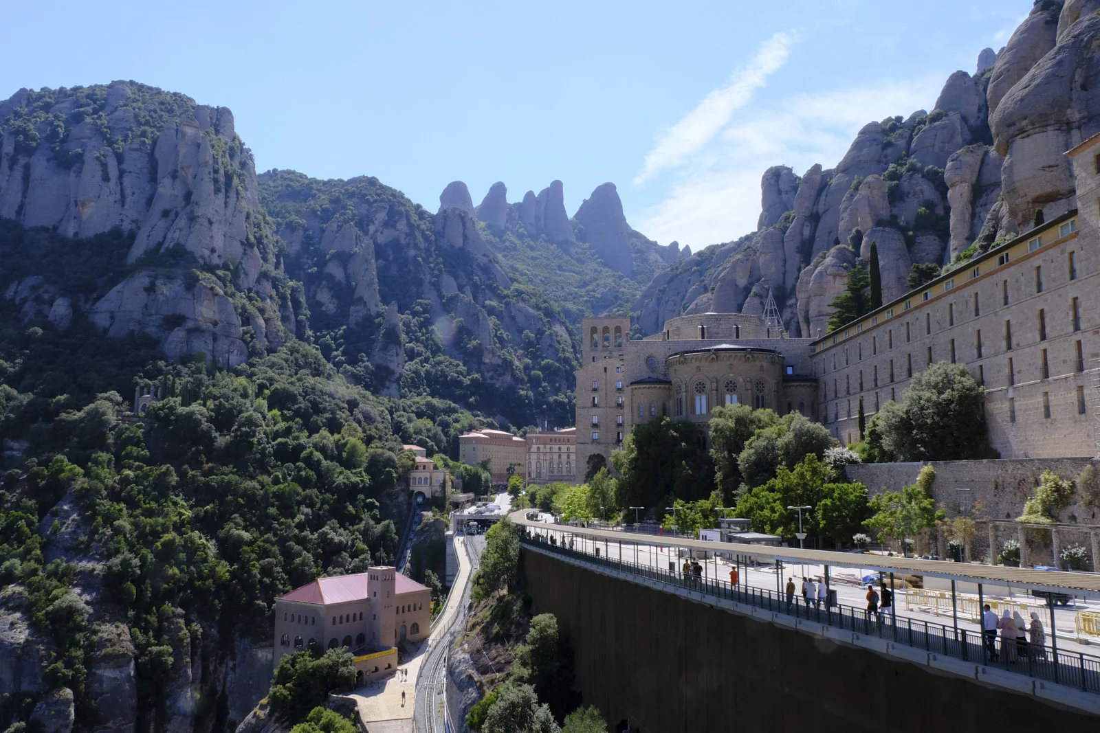 The basilica apse, monastery buildings, and funicular at Montserrat, with the rock peaks rising behind them.
