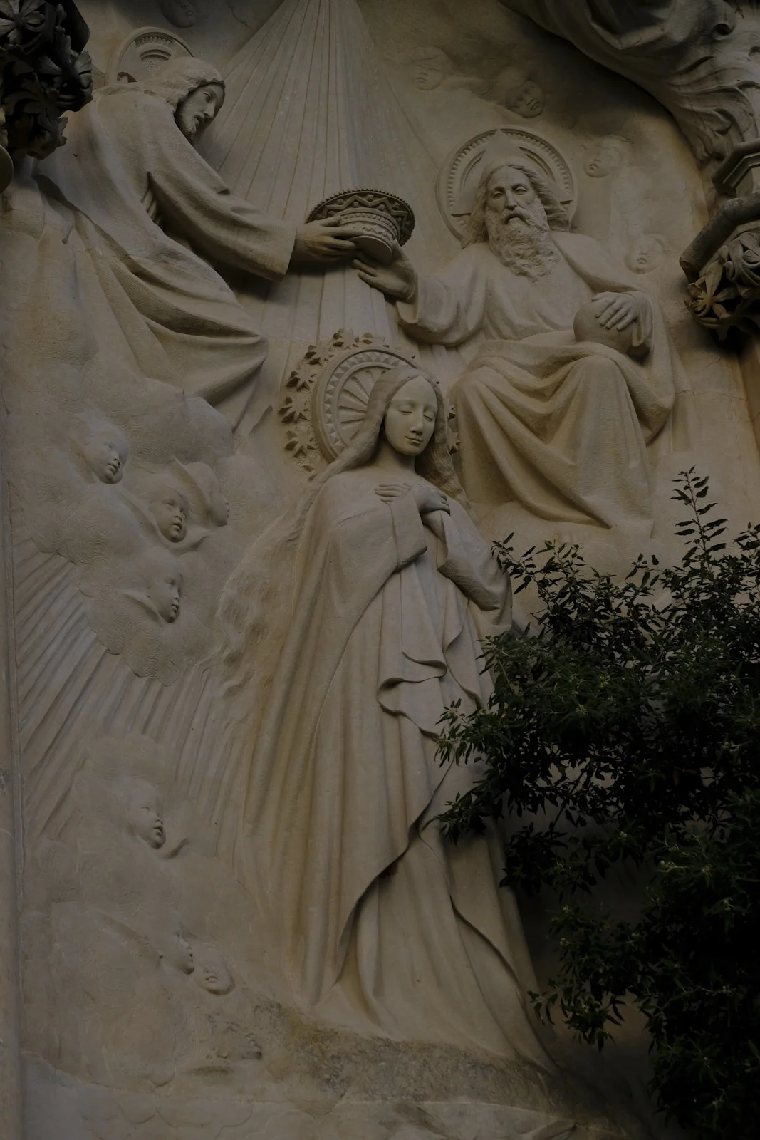 A stone relief of Christ crowning Mary, with God the Father seated beside her, on the Monumental Rosary path at Montserrat.