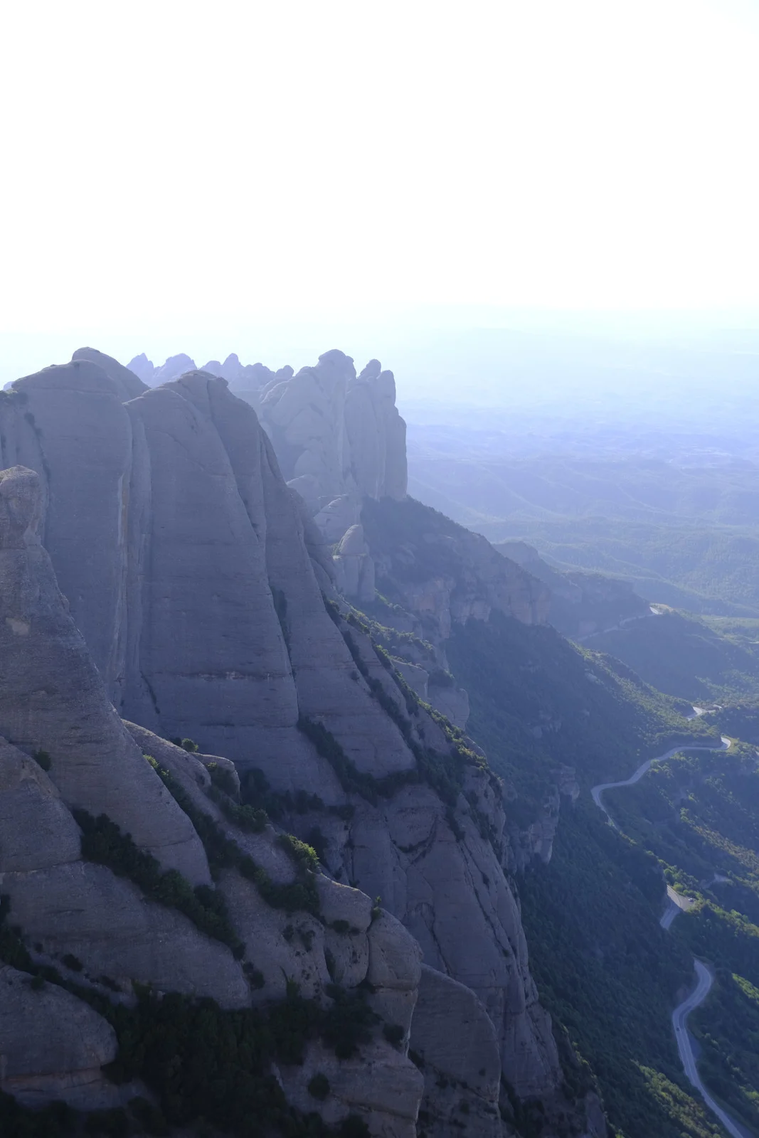 A wall of serrated rock peaks at Montserrat, with the hairpin road to the monastery below.