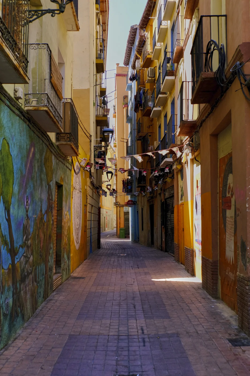 Banners stretch across a narrow lane of balconies and wall paintings in the old town of Zaragoza.