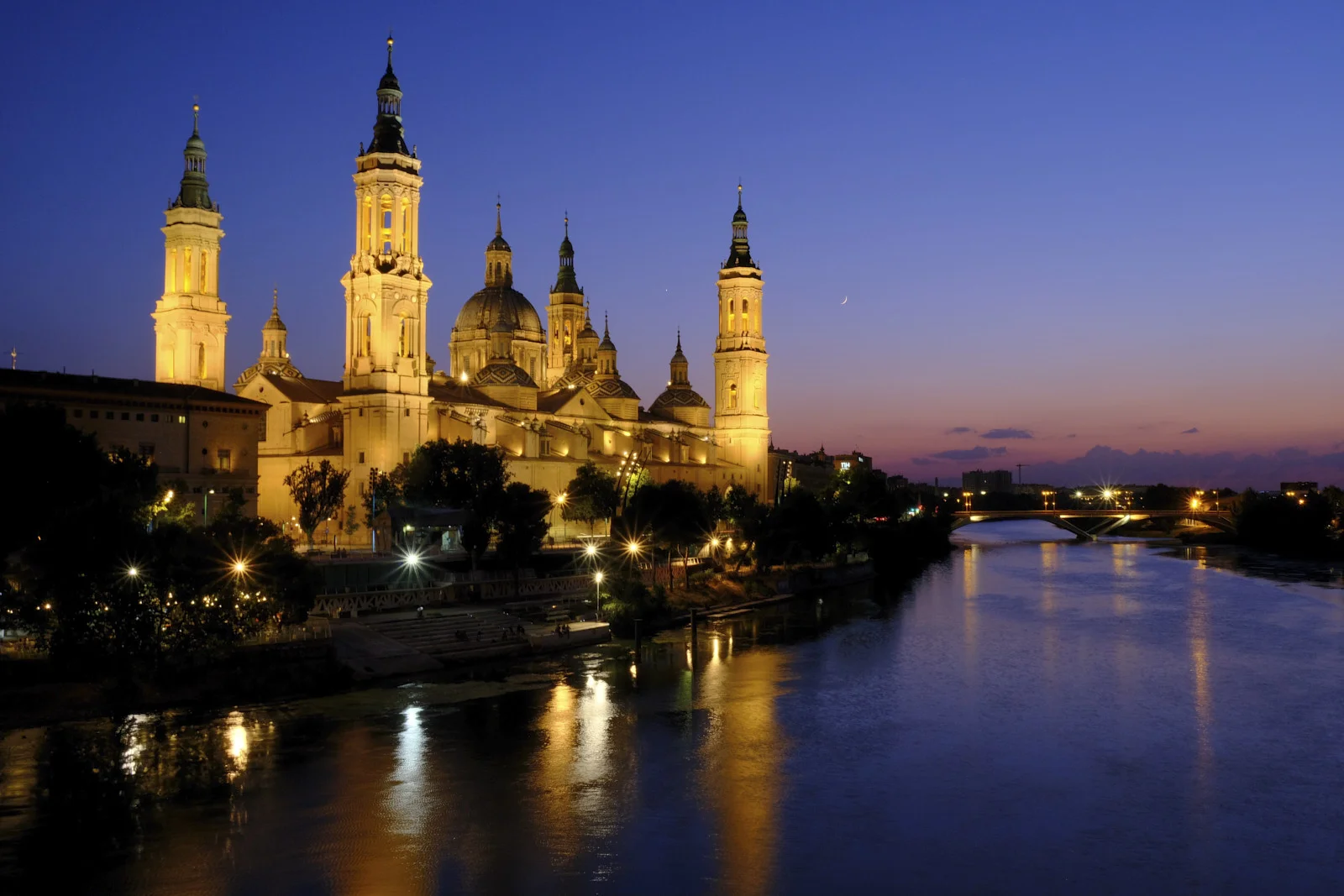 The Basilica of Our Lady of the Pillar in Zaragoza stands on the far bank of the Ebro, with a bridge to the right.