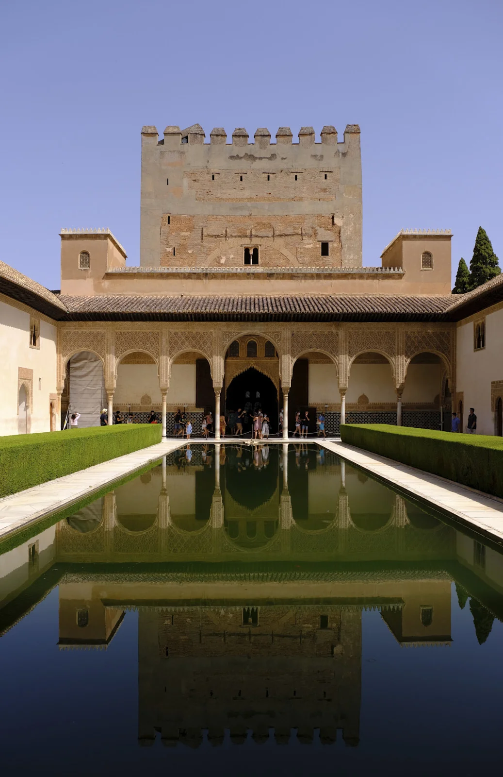 The long pool of the Court of the Myrtles runs between myrtle hedges toward the north gallery, with the Comares Tower above it.