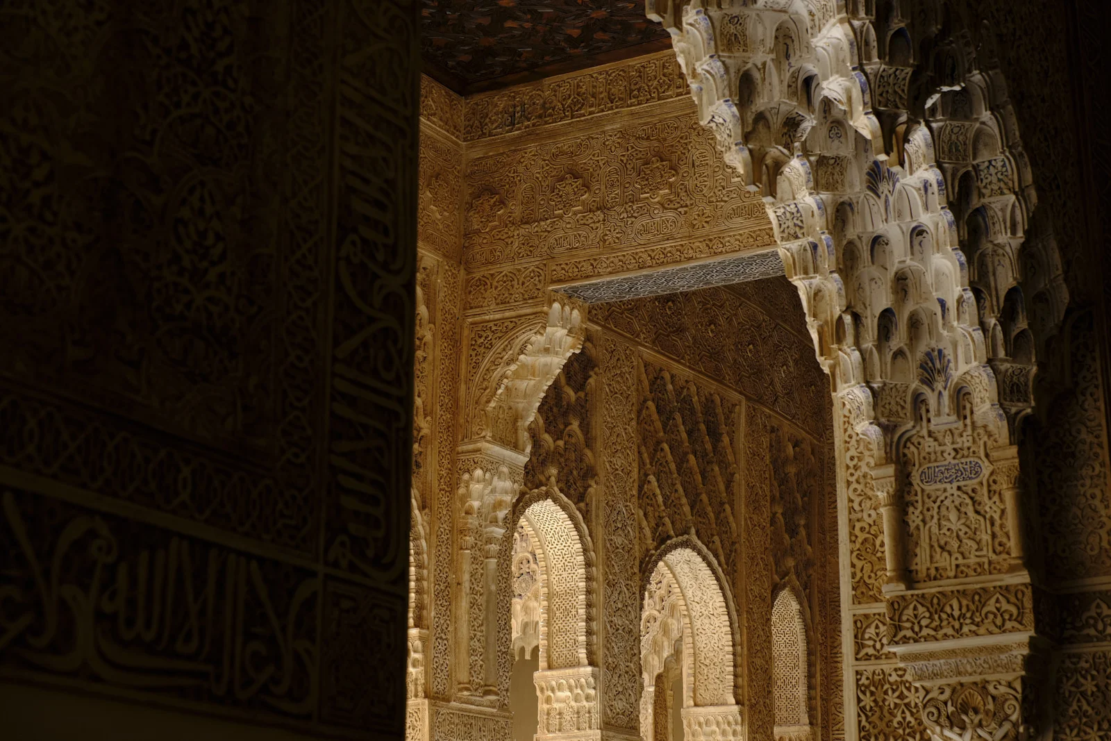 Carved stucco walls and a cluster of muqarnas arches fill a palace interior.
