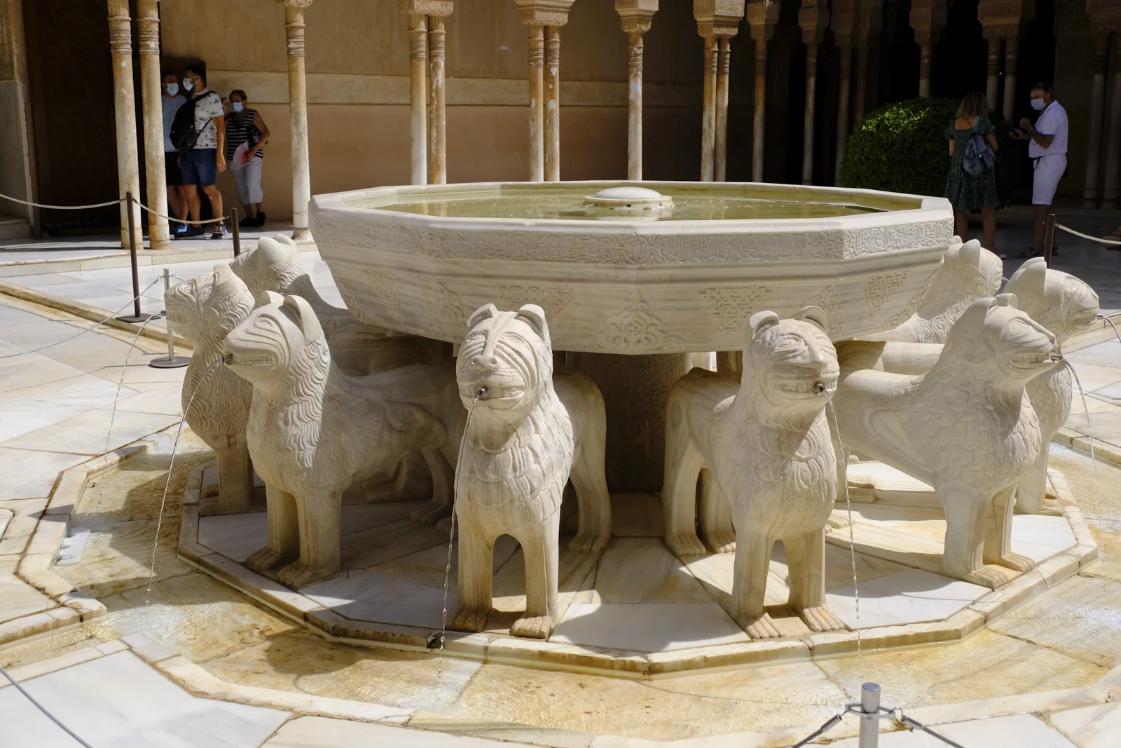 Stone lions support the basin of the fountain in the Court of the Lions, with the court's columns behind them.