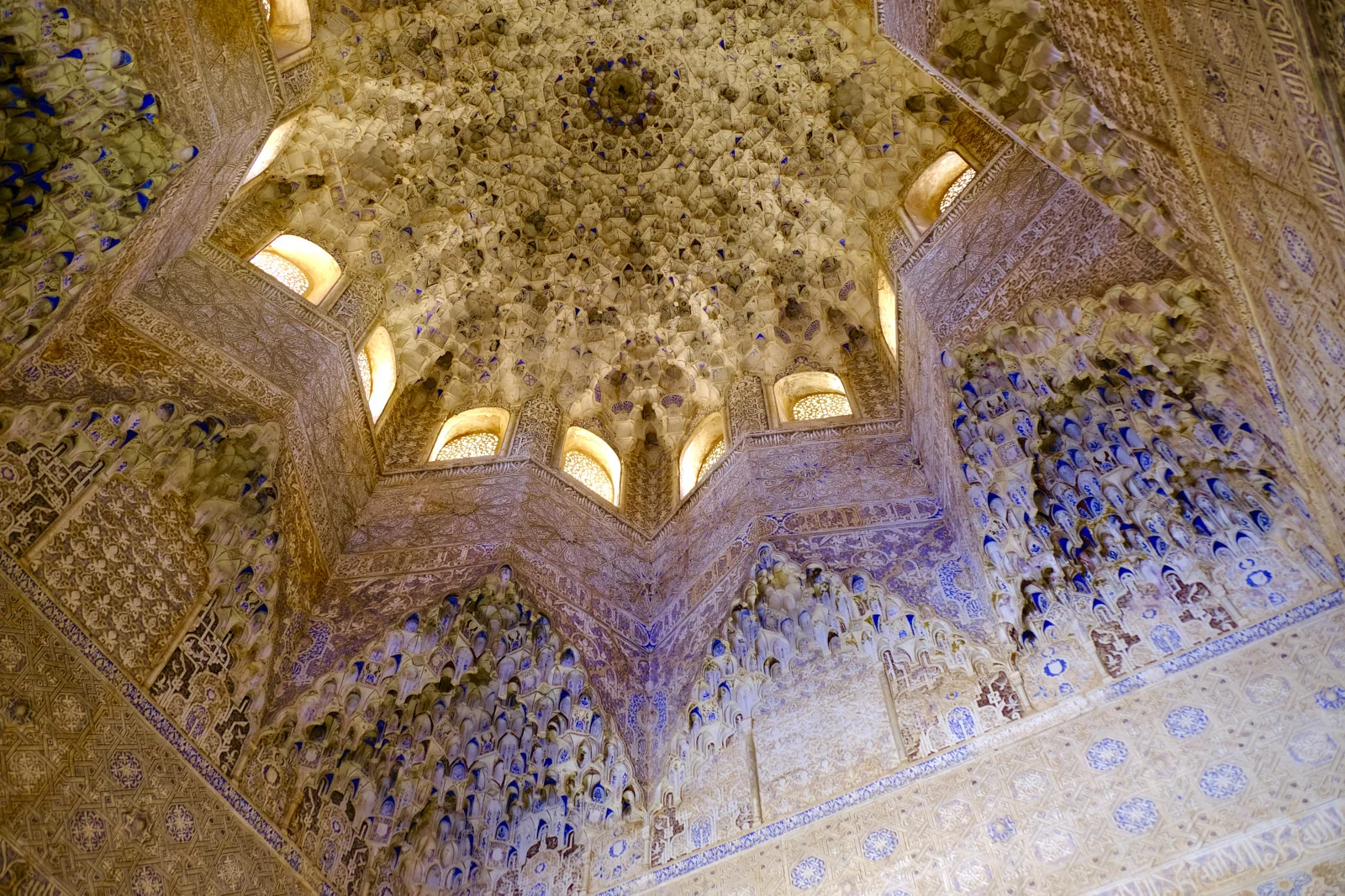 An eight-sided muqarnas dome, with lattice windows in the drum and carved stucco on the walls below.