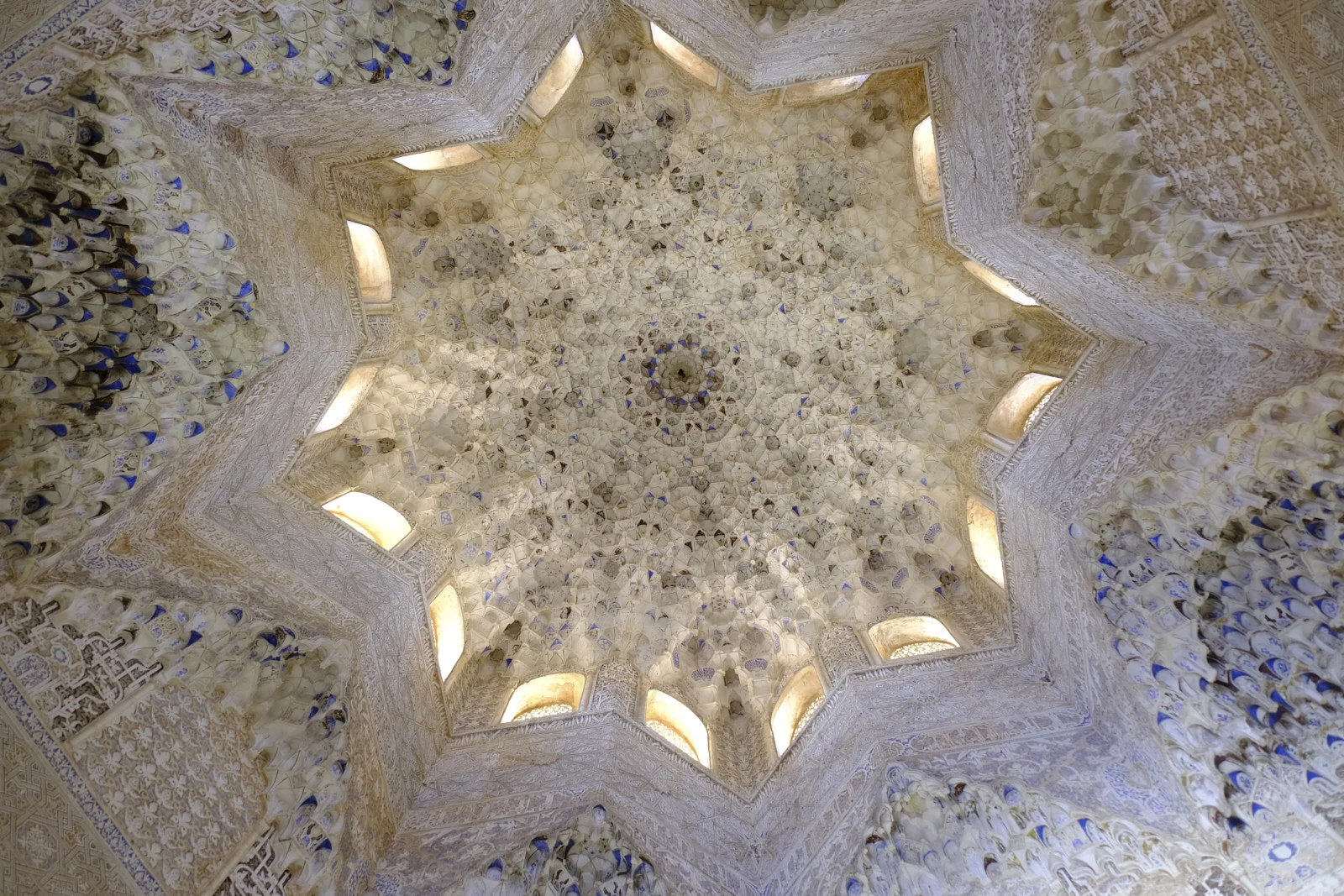 The eight-pointed star of a muqarnas vault, ringed by small windows, fills the ceiling.