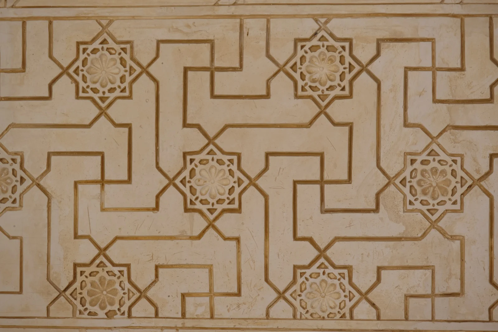 A plaster panel of eight-pointed stars joined by an angular interlaced band.