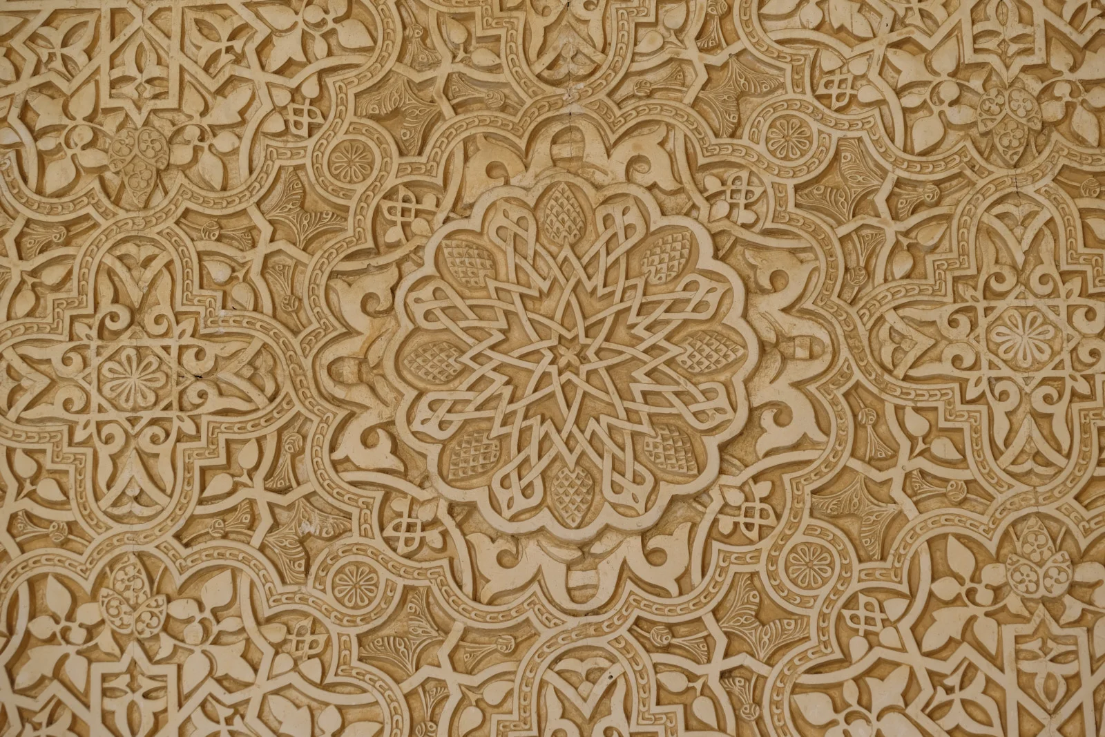 A central floral rosette of interlaced strapwork surrounded by smaller geometric and plant motifs in carved stucco.