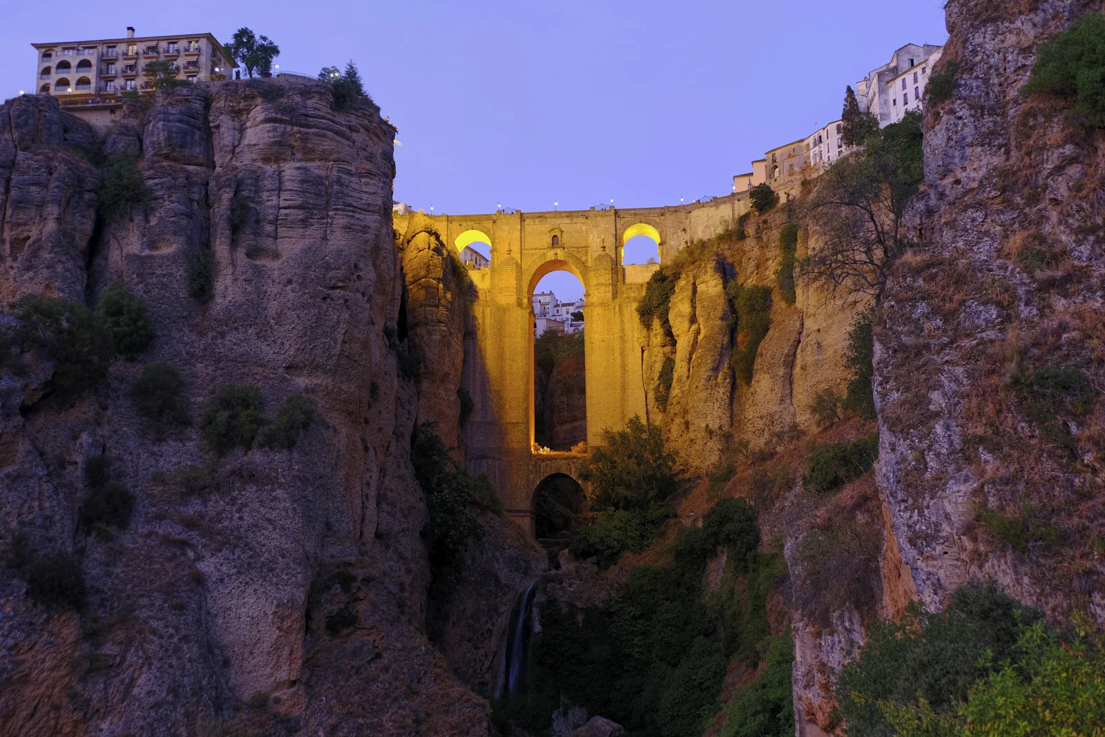Puente Nuevo crosses the gorge at Ronda above a waterfall, with a large building on the cliff at left.