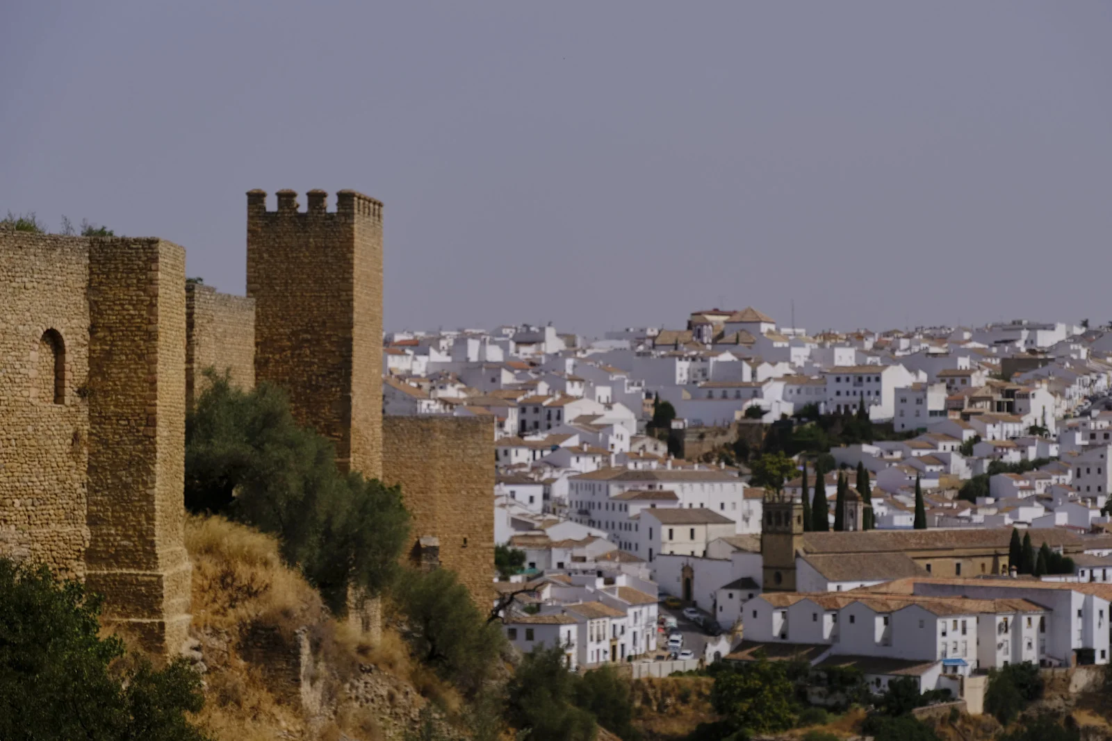 A crenellated tower and the city walls overlook the old town of Ronda.
