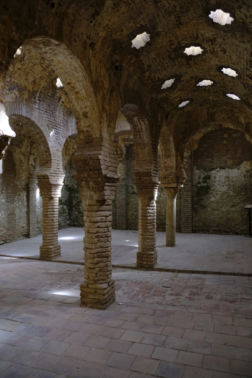 Horseshoe arches and columns fill the Arab baths in Ronda beneath a vault pierced by star-shaped openings.