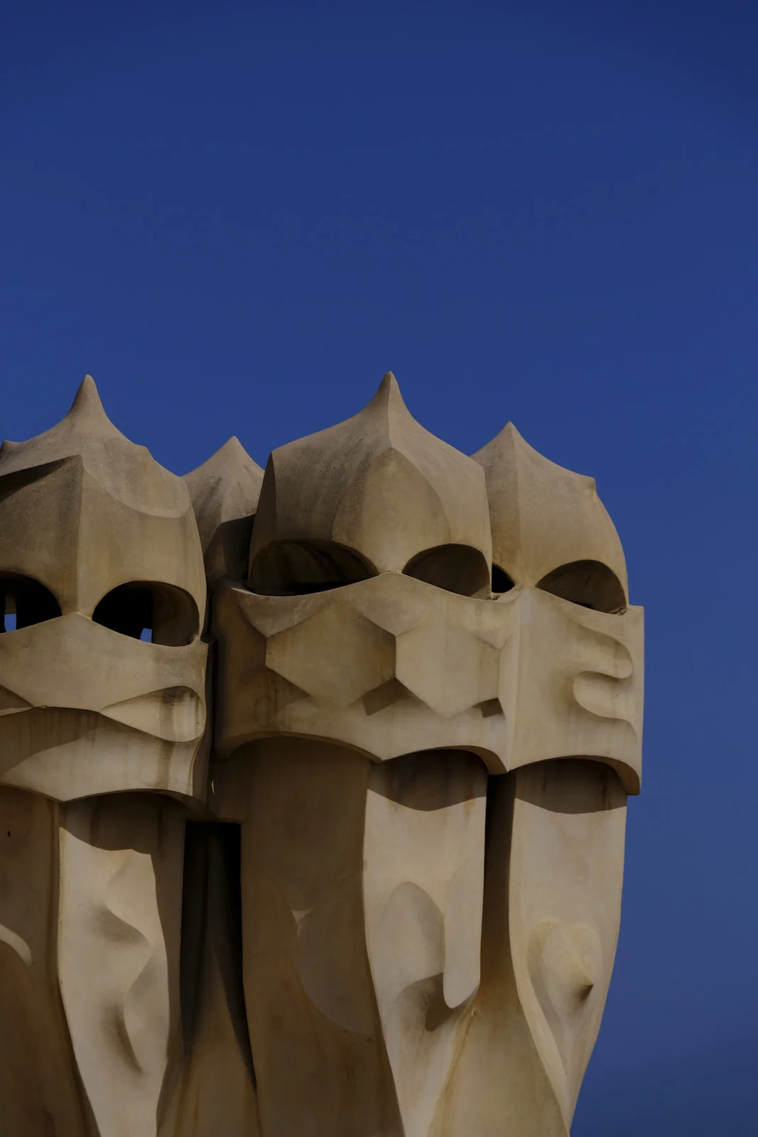 A group of chimney pots with pointed tops stands on the roof of La Pedrera in Barcelona.