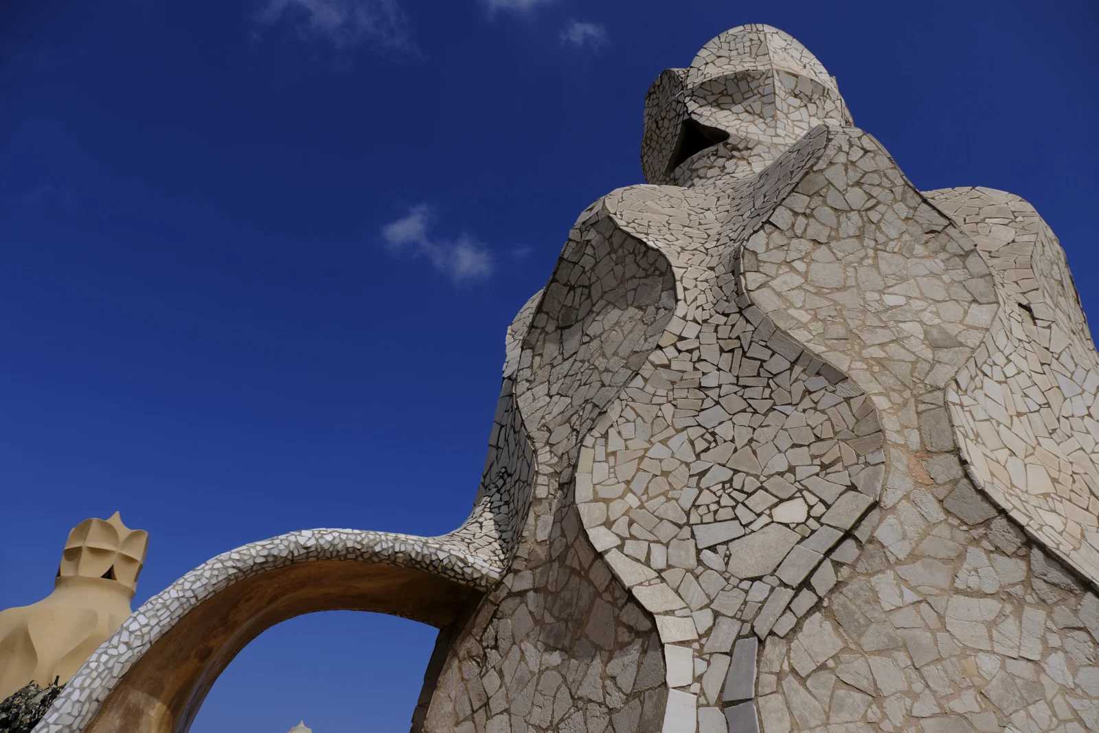 A broken-tile stair tower with an arch stands on the roof of La Pedrera in Barcelona.