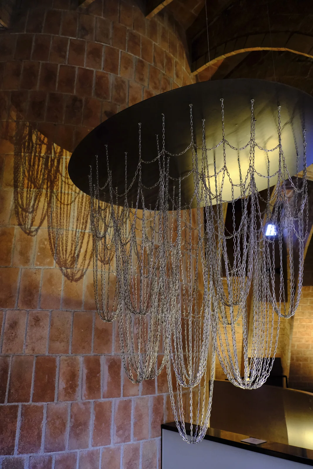 Chains hang in catenary curves from a round plate in the attic of La Pedrera in Barcelona.