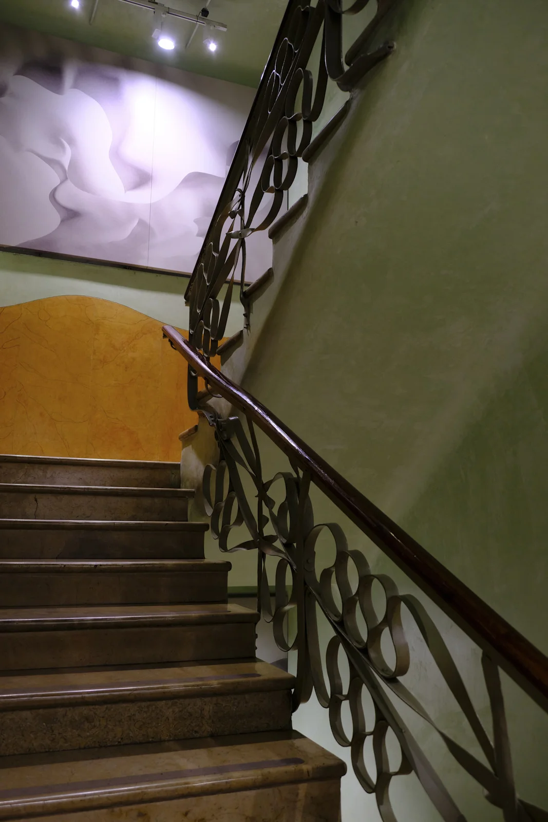 A looping iron rail runs beside a stone stair inside La Pedrera in Barcelona.