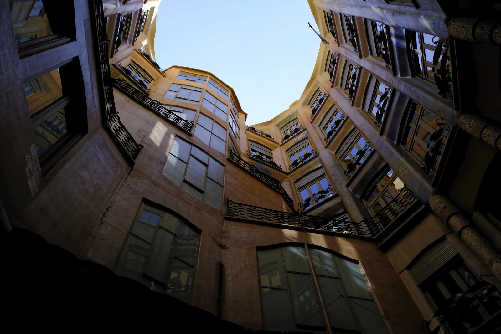 The courtyard walls of La Pedrera in Barcelona rise past rows of windows and iron balconies.