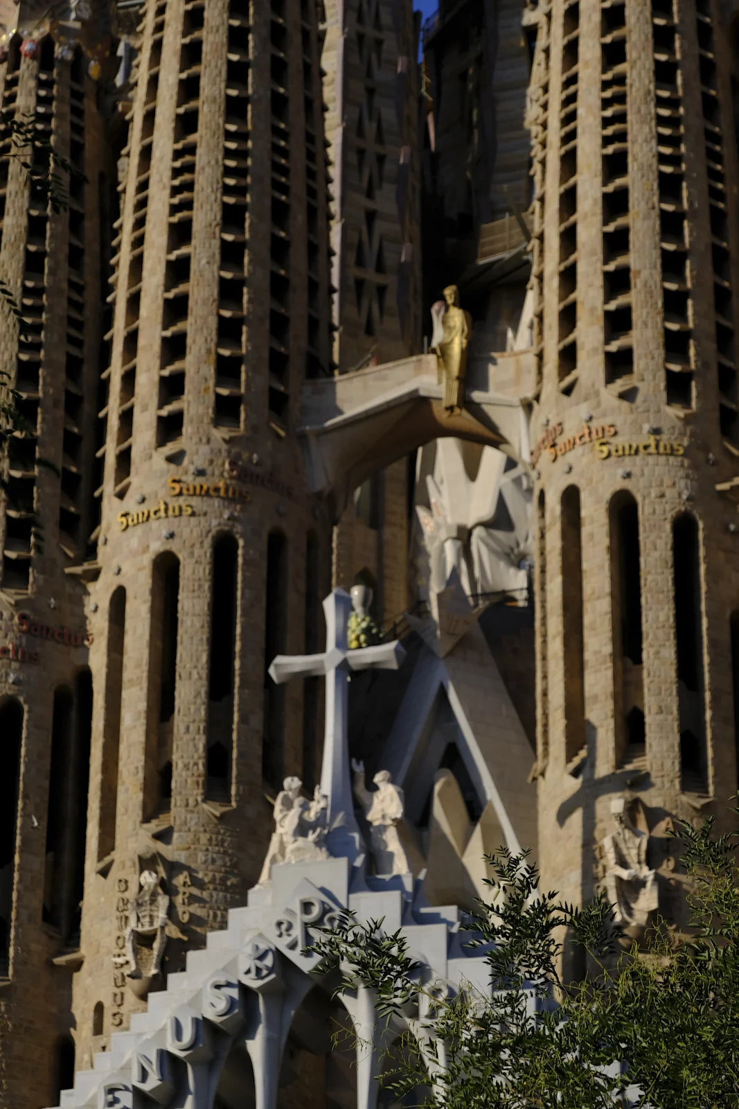 The Passion facade of the Sagrada Família in Barcelona shows the cross, sculpted figures, and bell towers inscribed Sanctus.