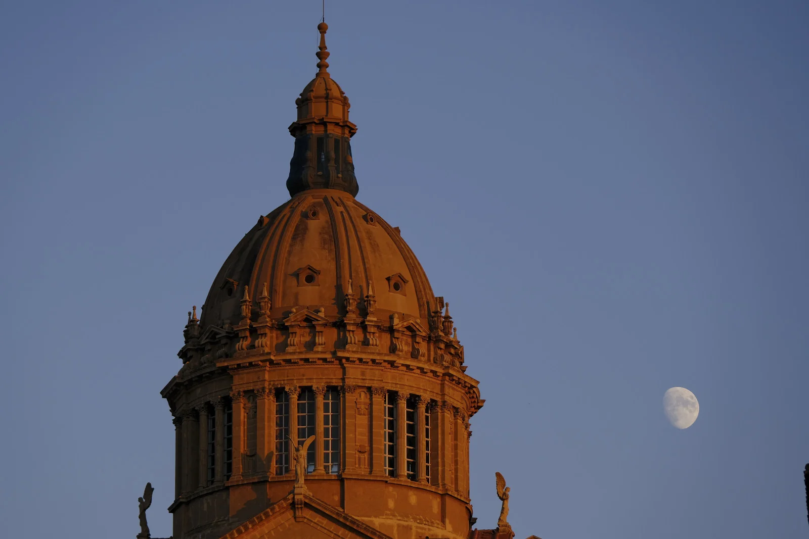 A ribbed dome with a lantern, columns, and winged statues stands in Barcelona.