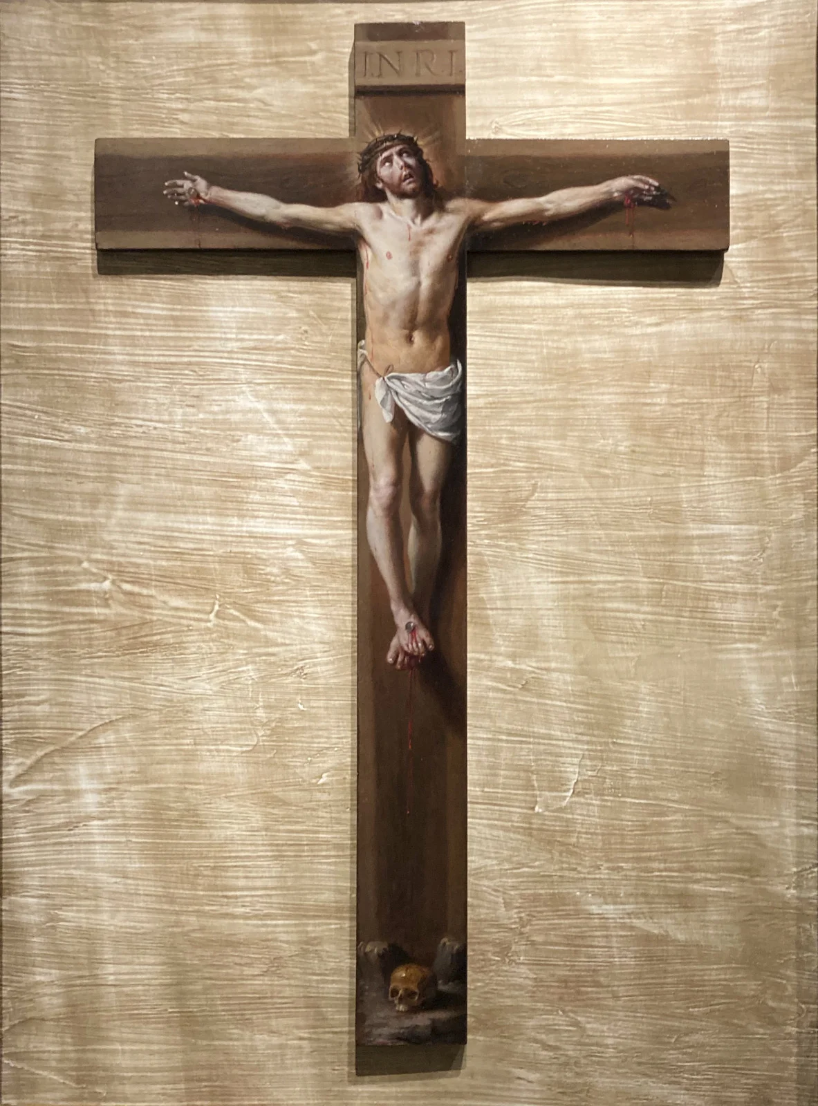 A painting of Christ on the cross, marked INRI and with a skull at the foot, hangs on a wall in Zaragoza.