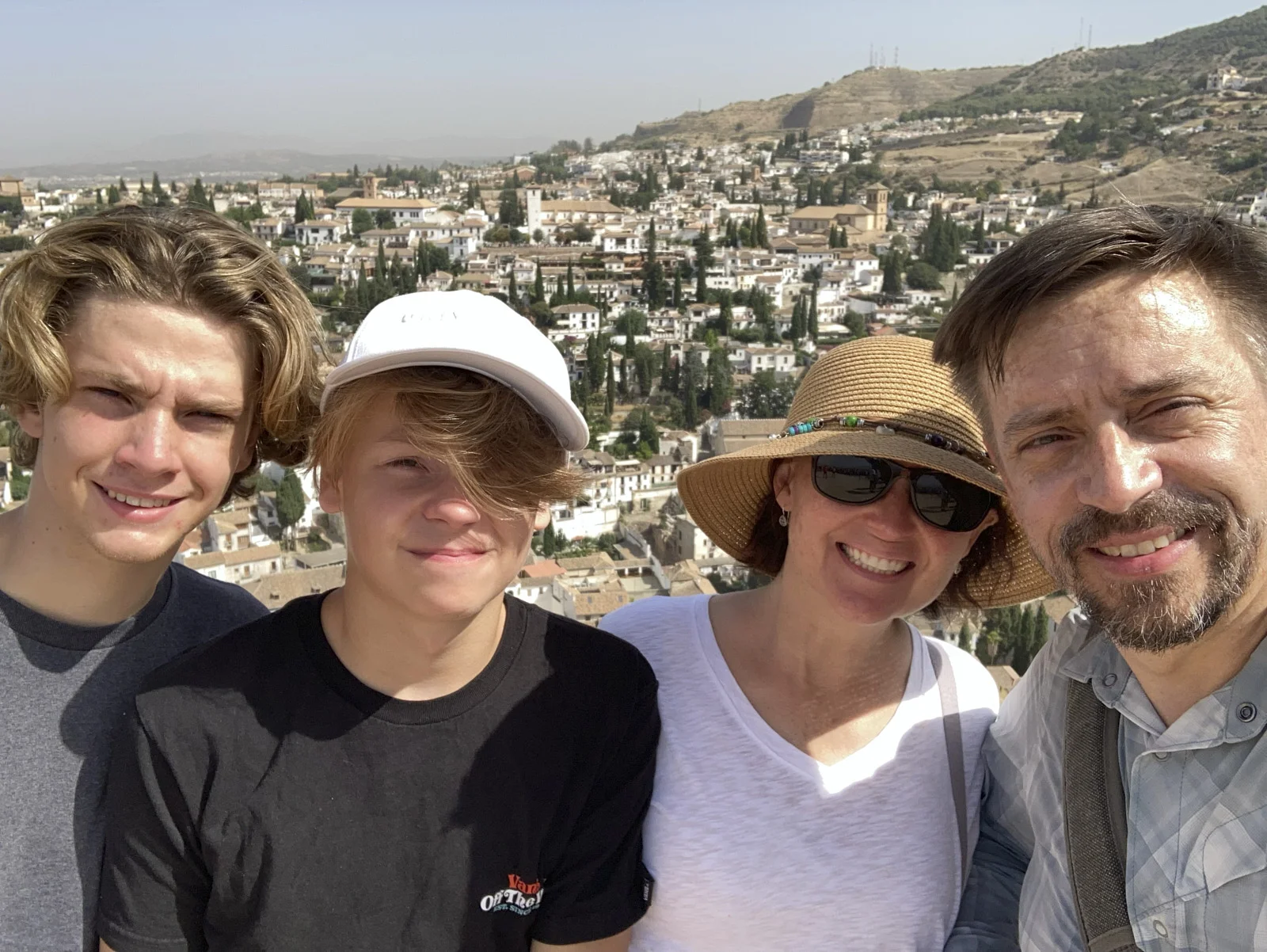 Four people stand on the Torre de la Vela with the houses of the Albaicín behind them.