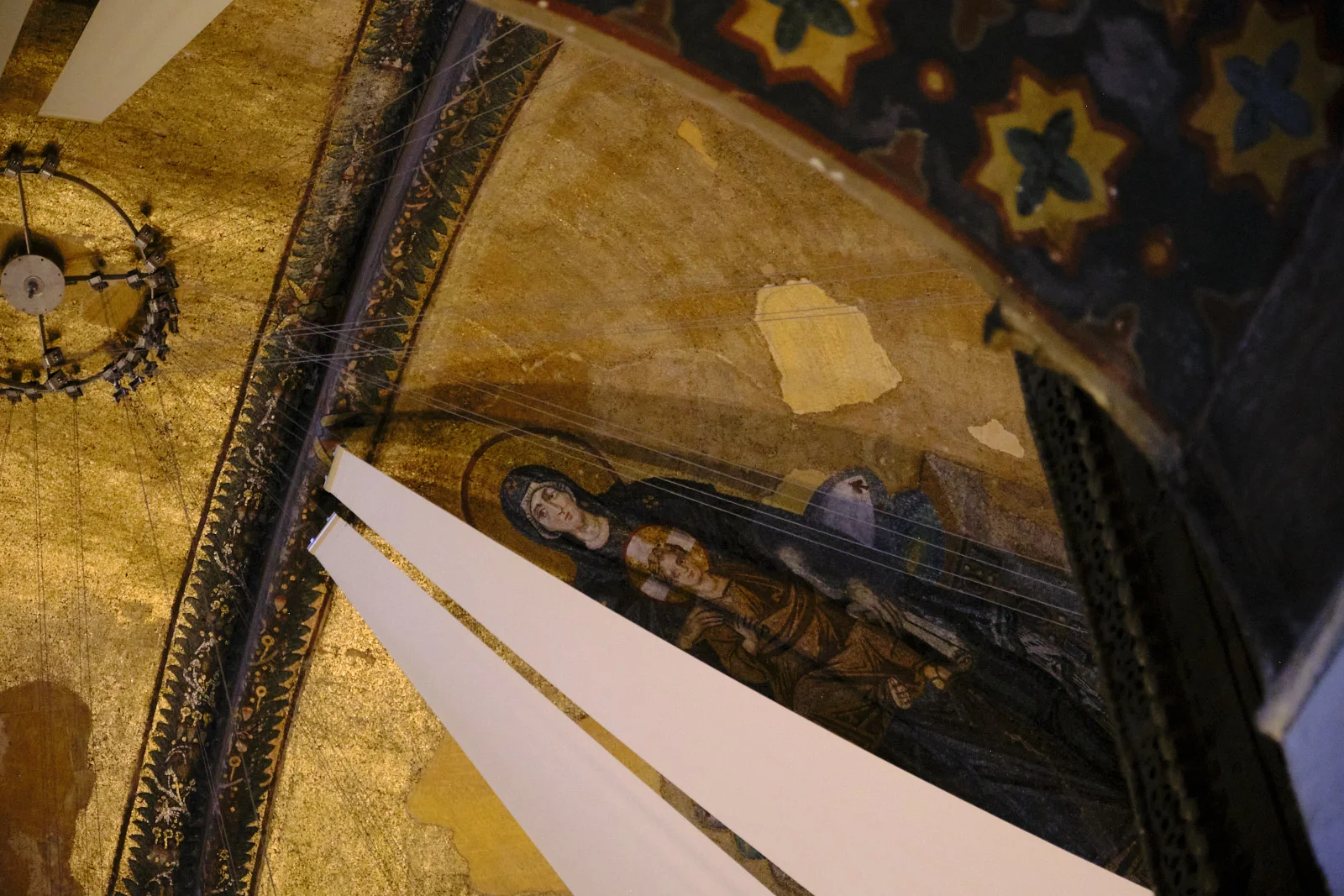 The gold mosaic of the Virgin and Child high in Hagia Sophia, partly blocked by white panels and thin wires.