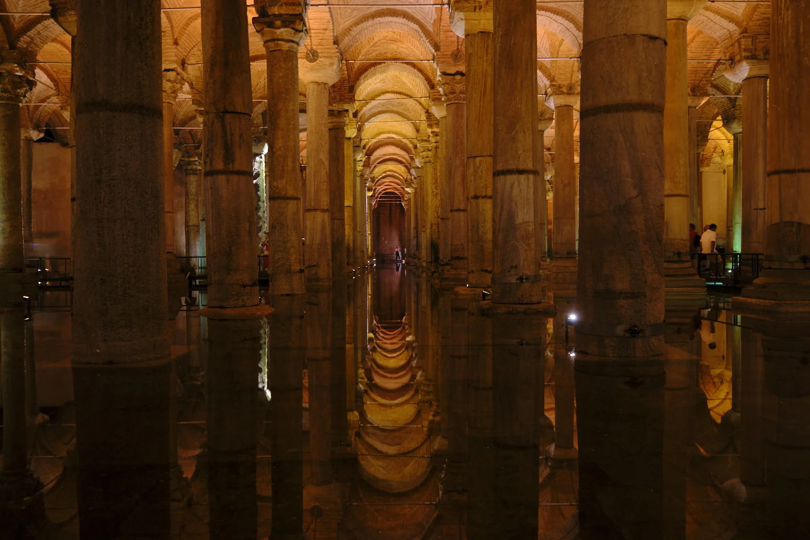 Rows of stone columns and brick arches in the Basilica Cistern are reflected in dark, still water.
